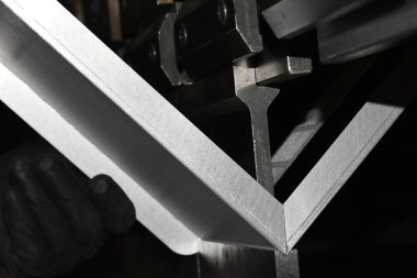 İşçi, atölyede metal baskı makinesi çalıştırıyor..