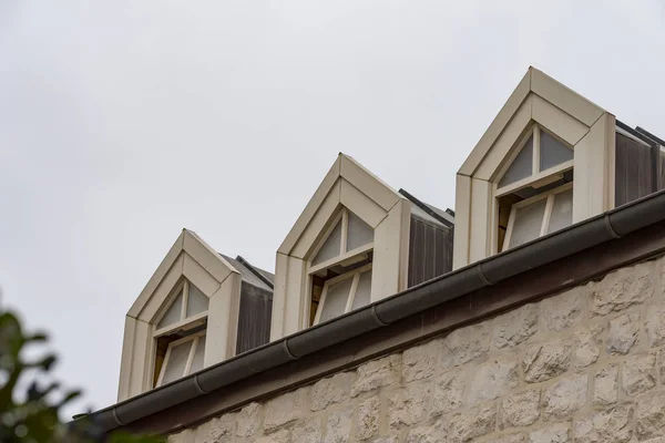 Roof with three beautiful white dormer windows. Ancient round dormer windows in rooftop. Symmetrical view on roof with three garret windows