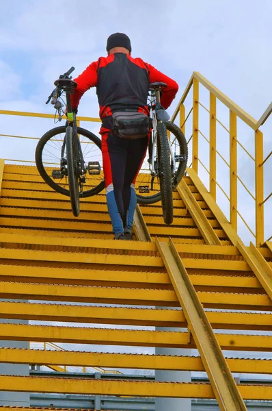 a man carrying two bicycles up the stairs