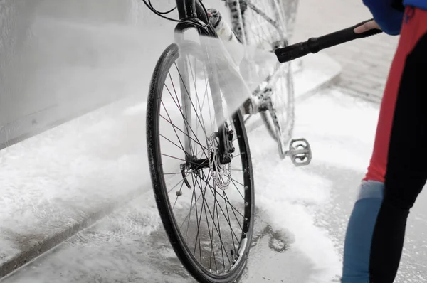 man washing the bike with a strong jet of water, washing the bike after the trip