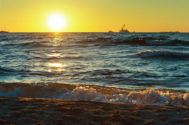 red yellow sunset on the sea shore in the surf of the waves of the Baltic sea and a magnificent sunrise clipart