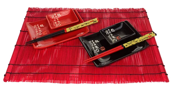 Czerwony i czarny zestaw naczyń dla sushi na czerwony mat drewnianych. — Zdjęcie stockowe