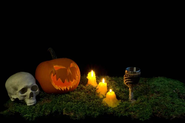 Calabaza de Halloween, cráneo humano, copa y velas brillando en th — Foto de Stock