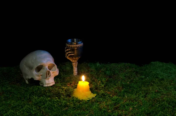 Halloween crânio humano, cálice e velas brilhando no escuro em — Fotografia de Stock