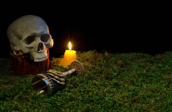 Halloween teschio umano, calice e candele incandescenti al buio su — Foto Stock