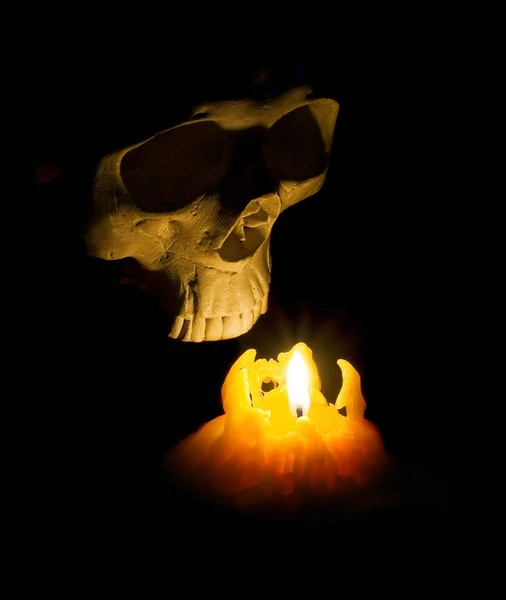 Halloween fantasma crânio humano sai da escuridão iluminado com vela — Fotografia de Stock