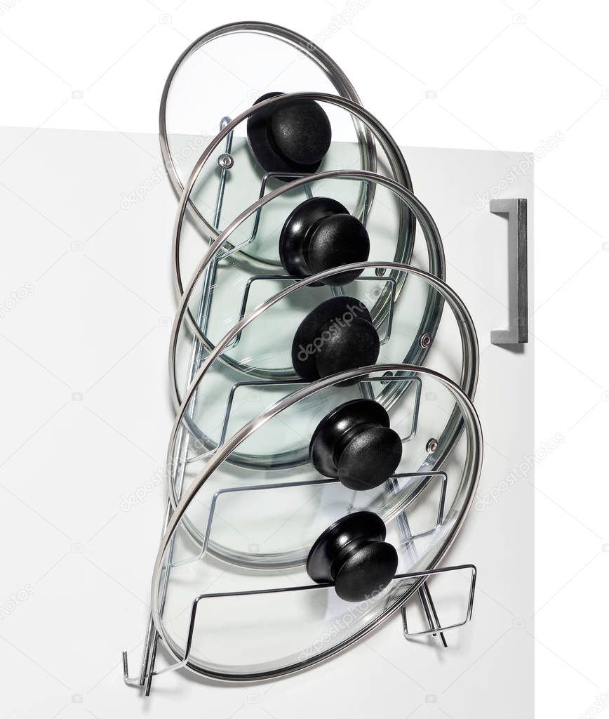 A hanger with glass lids for cooking pots hung on the door of a 