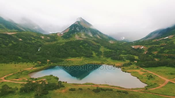 Flygfoto. Reflektioner av berget i en sjö. Nära förhållningssätt till vattenfall av dron. — Stockvideo
