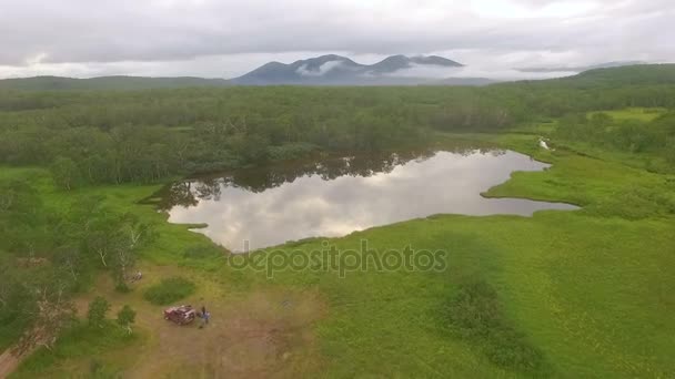 Luftaufnahme. fliegen über den See zum Hubschrauber. der See spiegelt Wald und Wolken wider — Stockvideo