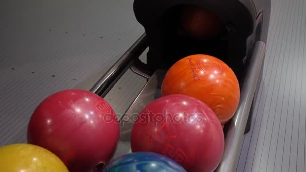 Крупный план разноцветных шаров для боулинга, человек берёт мяч. Человек играет в боулинг замедленной съемки — стоковое видео
