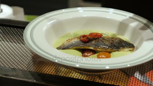 Чоловічі руки в латексні рукавички кладуть варену рибу в тарілку з овочами і білим соусом. готувати — стокове відео