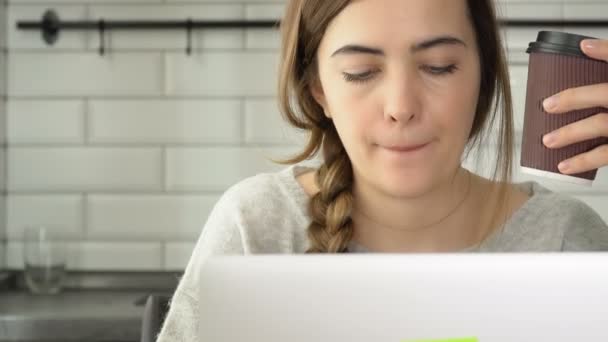 Meisje werkt voor een laptop. De schrijver schrijft de tekst en drinkt koffie. Een vrouw werkt een laptop — Stockvideo