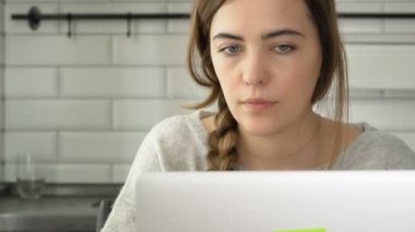 Kız bir laptop için çalışır. Kadın metni yazdı ve okumak. Evde, freelancing çalışma
