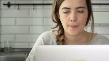 Kız bir laptop için çalışır. Kadın metni yazdı ve okumak. Evde, freelancing çalışma