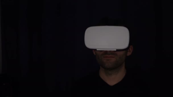 Человек надевает виртуальную наушницу. Человек в очках виртуальной реальности. Человек с гарнитурой — стоковое видео