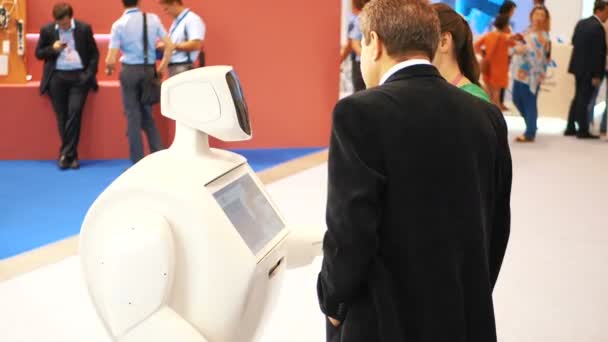 Novosibirsk Rusia - 29 de junio de 2017: Robot se comunica con las personas en las exposiciones. Robot con pantalla interactiva se comunica con los visitantes en un centro de negocios. Gente usando su pantalla táctil — Vídeos de Stock