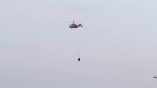 Helicóptero cae abeto de agua. Un helicóptero combate un incendio forestal gigantesco en una ladera seca de la montaña, dejando caer cientos de galones de agua en las llamas. Helicóptero militar. Emergencia — Vídeo de stock