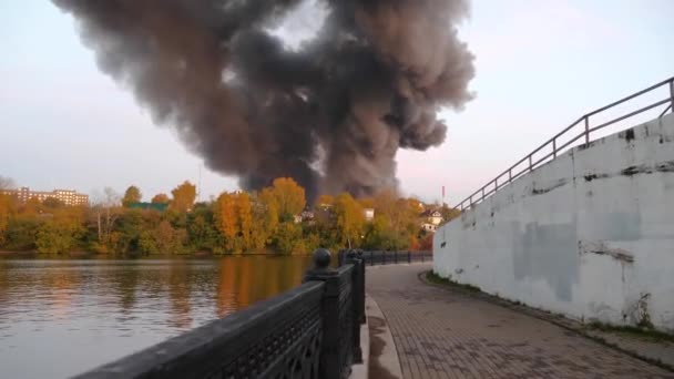 Fuego en la ciudad. Hay mucho humo detrás del bosque. Incendio de un centro comercial en la ciudad. La tienda está en llamas. Fuego humo y cenizas en Moscú. Clubes de humo se elevan en el cielo. Medio ambiente — Vídeo de stock