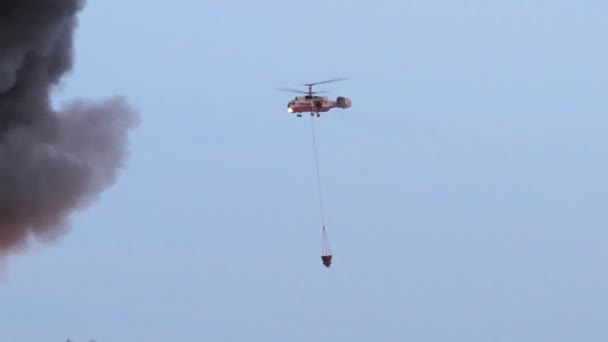 Ein Hubschrauber löscht ein Feuer in der Stadt. Löschen von Feuer mit Wasser aus der Luft. Flammen und Rauch aus dem Hubschrauber. ein Team von Feuerwehrleuten halten. Schlauch und löschte einen Hausbrand. Feuerwehreinsatz — Stockvideo