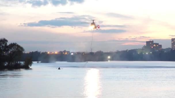 Вертолет собирает воду в реке, чтобы потушить пожар. Спасательная служба и пожарные тушат пожар. Вертолет завис в воздухе. Пожар в Москве, Россия. Военный вертолет — стоковое видео
