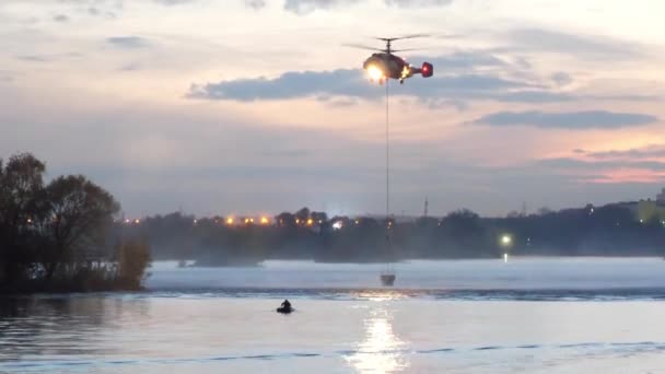 Helicóptero del Ministerio de Emergencias. El helicóptero recoge agua en el río para extinguir un incendio. El rescate — Vídeo de stock