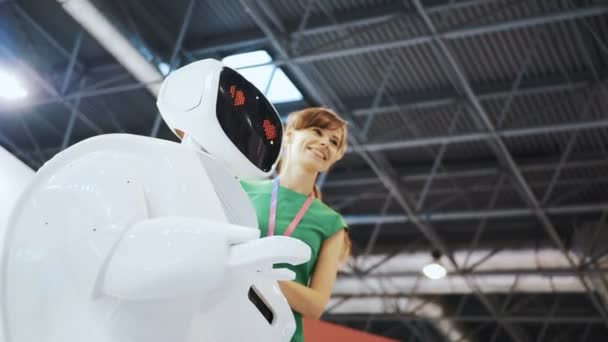 Roboter verliebte sich, die Emotionen des Roboters. Herz und Smiley. Positive Frau macht Selfies mit Roboter. Das Mädchen macht Selfie mit einem Roboter. nette Frau, die Bewegungen nach dem Roboter wiederholt. Lächelnde Frau — Stockvideo
