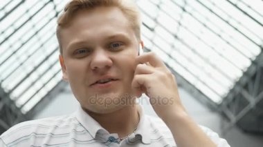 Adam kameraya gülümseyen ve telefonda konuşurken arıyor. Milan konuşmayı yürüyen mutlu genç adam. şehirde gerçek gülümseyen mutlu sevimli beyaz adam. Genç gülümseyen ve kameraya bakarak adam