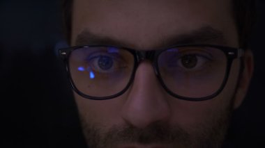 Portre adam bitcoins bitcoin çiftliğinde kazanır. Çocuk geceleri internet sörf bardaklarda closeup çekim. Genç adam karanlıkta onun tablet okuma kapatın. Siyah arka planda odak. Ağır çekim