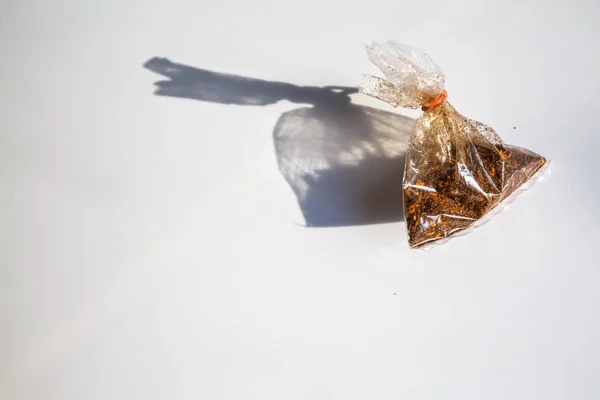Кайенский перец в пластиковом пакете на белом фоне — стоковое фото