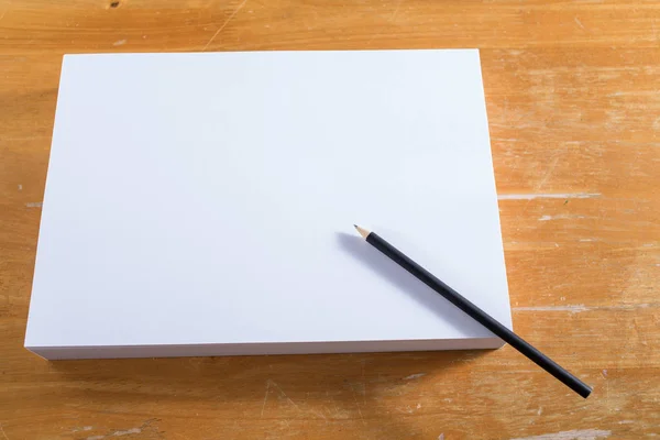 Dokument white paper s černou tužkou na dřevo stůl — Stock fotografie