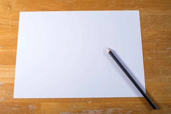 Ahşap masa üzerinde siyah kalem beyaz kağıt — Stok fotoğraf