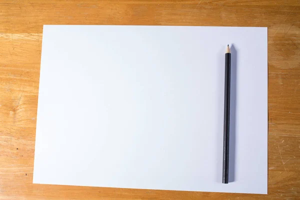 Ahşap masa üzerinde siyah kalem beyaz kağıt — Stok fotoğraf