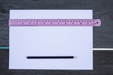 Ahşap doku arka plan üzerinde beyaz kağıt, siyah kalem, pembe cetvel