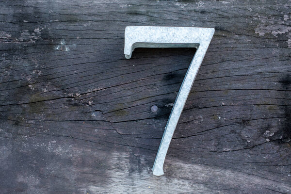 Number 7 (seven) made  from zinc on wood texture background