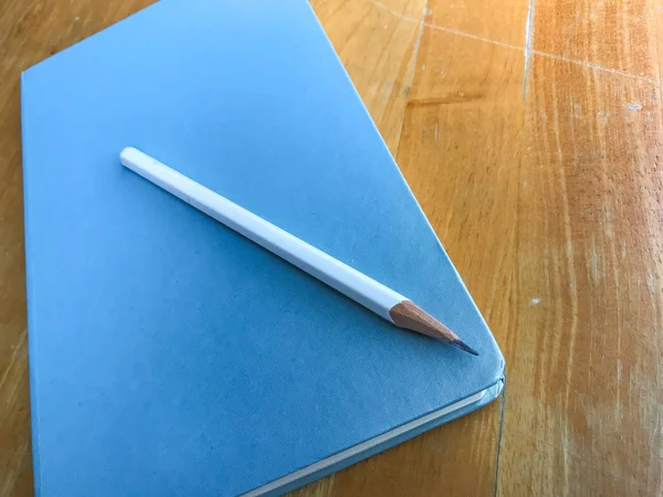 Jegyzetfüzet-val fehér ceruza, fa háttér, közelről — Stock Fotó