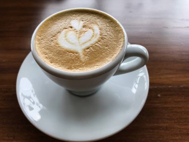 Ahşap masa arkasında bir fincan kahve.