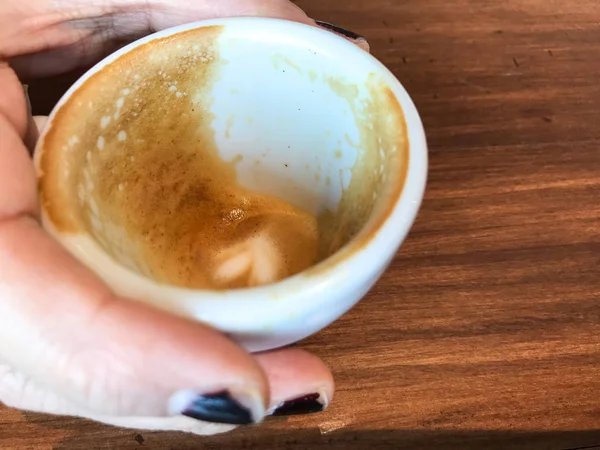 女性の手 (爪に塗られたゴールデン ローズ色) 持ち株コーヒー カップの木製の背景 — ストック写真