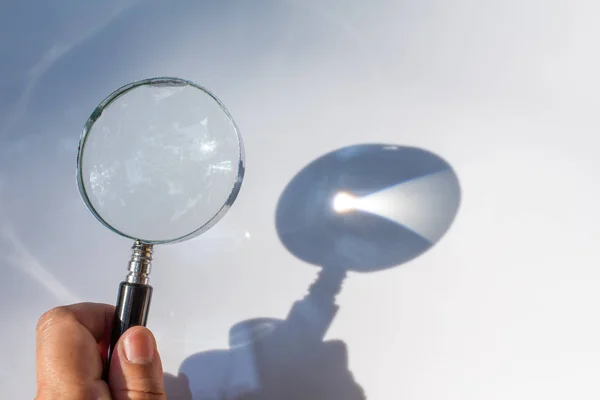 Mano sinistra con vecchia lente d'ingrandimento su sfondo bianco, Luce e ombra — Foto Stock