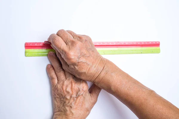Руки пожилой женщины держат линейку с треугольным мел портной изолированы на белом фоне, О портной — стоковое фото