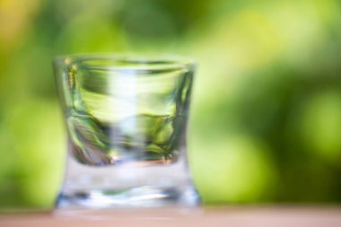 Bokeh yeşil bahçe arka planında, ahşap masanın üzerinde saydam temiz su bardağı, Makro şat ve Sağlıklı İçecek kavramını kapat