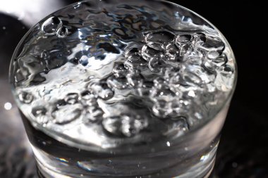 Şeffaf camda yüzen temiz su kabarcıkları, Makro çekimleri kapat, Seçici odak, Sağlıklı içecek kavramı