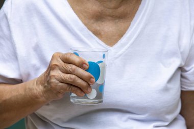 Kıdemli kadının sağ eli bir bardak su içiyor, sağlıklı bir kavram, yakın çekim.