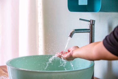 Musluktan eline akan su, yeşil lavabo, banyo konsepti.