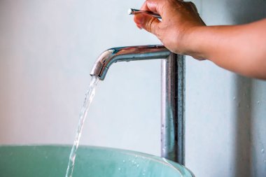 Musluktan eline akan su, yeşil lavabo, banyo konsepti.