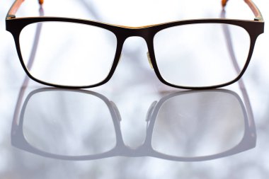 Black shortsighted or nearsighted eyeglasses on white acrylic table background, Close up & Macro shot, Selective focus, Reflection, Optical concept