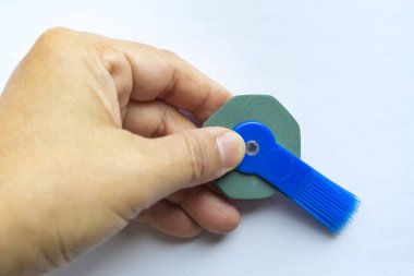 Kadının sol elinde fırçayla silgi, yakın çekim, kırtasiye konsepti.