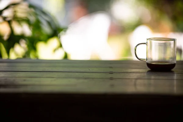 コーヒーグラスカップにコーヒーの汚れが付着し その後 ぼんやりと緑の庭の背景にある木製のテーブルの上にそれを飲んだ後 ショットを閉じる 選択的な焦点 — ストック写真