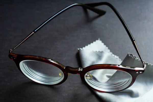 Brown shortsighted or nearsighted eyeglasses with microfibre cleaning cloths, On black background, Close up & Macro shot, Selective focus, Optical concept