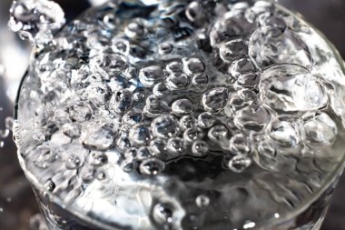 Şeffaf camda yüzen temiz su kabarcıkları, Makro çekimleri kapat, Seçici odak, Sağlıklı içecek kavramı