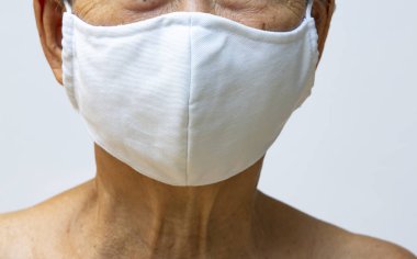 Üst düzey kadın el yapımı pamuk maske takıyor, beyaz arka planda cerrahi maske, ön görüş, yakın çekim, odaklanma, covid19, Coronavirus, Bakteri, Sağlık Hizmetleri,